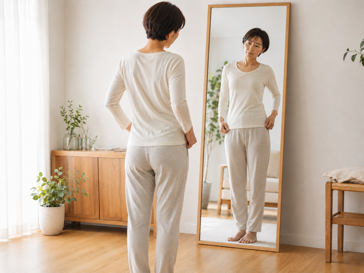 鏡を見ながら自分の姿勢やシルエットを確認する女性